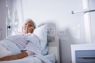 Thoughtful senior woman lying on bed