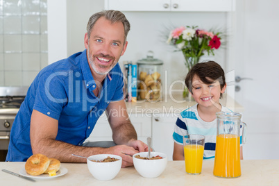 Portrait of father and son having breakfast in kitchen
