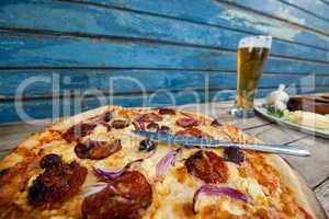 Italian pizza served with glass of beer on wooden plank