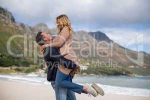Mature man holding mature woman on beach