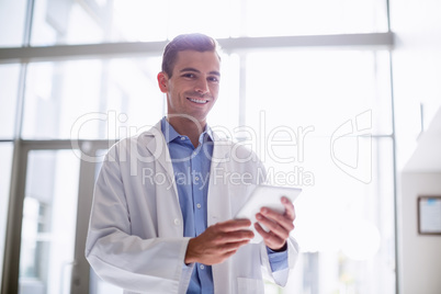 Portrait of doctor using digital tablet in hospital corridor