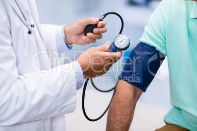 Mid section of doctor checking blood pressure of a patient