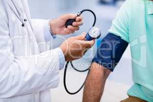 Mid section of doctor checking blood pressure of a patient