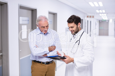 Doctor and patient discussing on clipboard in corridor