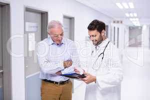 Doctor and patient discussing on clipboard in corridor