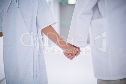 Doctor and patient holding hands while standing
