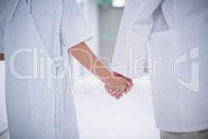 Doctor and patient holding hands while standing