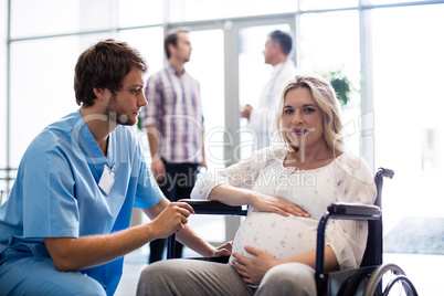 Male doctor talking to pregnant woman in wheelchair