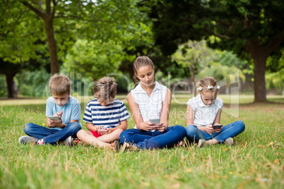 Kids using mobile phone in park