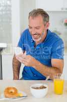 Man using mobile phone while having breakfast in kitchen