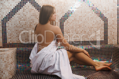 Topless girl wrapped in a bedsheet shot in sauna