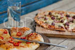 Italian pizza served with glass of water on wooden plank
