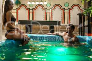 Young sexy pair bathing in luxurious swimming pool