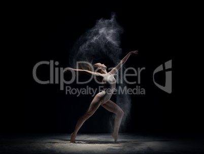 Athletic dancer in cloud of powder on the scene