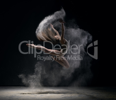 Girl in body jumps in dust cloud black background