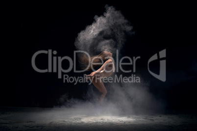Dancer in motion in cloud of powder, studio shot