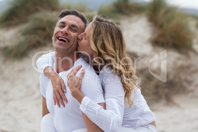 Mature man giving piggyback ride to woman on beach