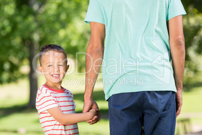 Son holding hands of his father in park