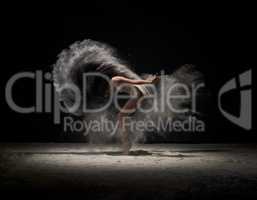 Dancer moving in cloud of white dust at studio