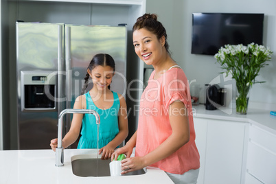 Mother assisting her daughter in cleaning vessel