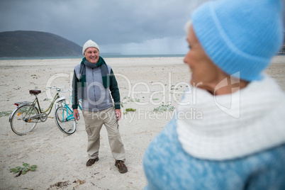 Senior couple standing with bicycles on the beach