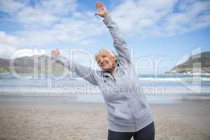 Senior woman doing stretching exercise on the beach