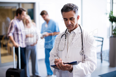 Male doctor writing on a clipboard