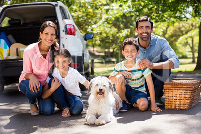 Happy family on a picnic sitting next to their car