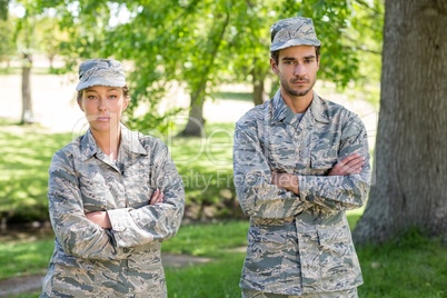 Portrait of a military couple standing with arms crossed in park