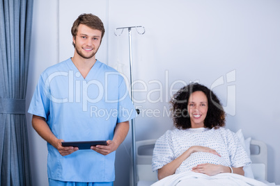 Portrait of smiling doctor and pregnant woman in ward