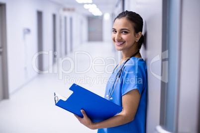 Portrait of female doctor holding file in corridor