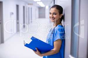 Portrait of female doctor holding file in corridor