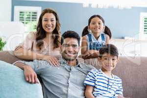 Portrait of happy parents and kids sitting on sofa in living room