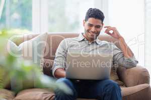 Man sitting on sofa and using laptop in living room