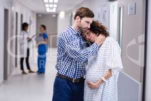 Man comforting pregnant woman in corridor