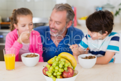 Smiling father and kids having breakfast in kitchen