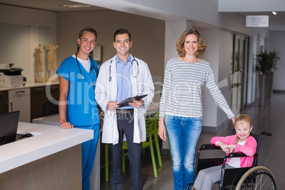 Doctors and woman standing with disable girl in corridor