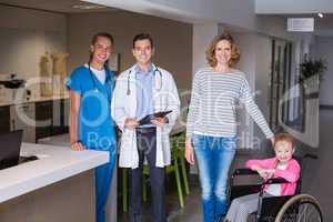 Doctors and woman standing with disable girl in corridor