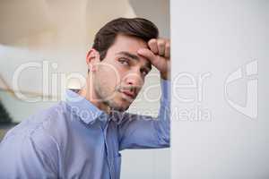 Worried businessman with hand on head leaning on wall