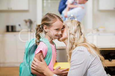 Woman kissing her daughter while going to school
