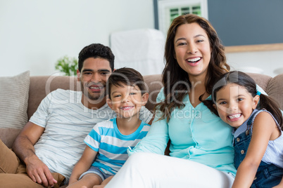 Portrait of parents and kids sitting on sofa in living room