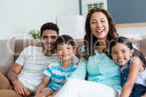 Portrait of parents and kids sitting on sofa in living room