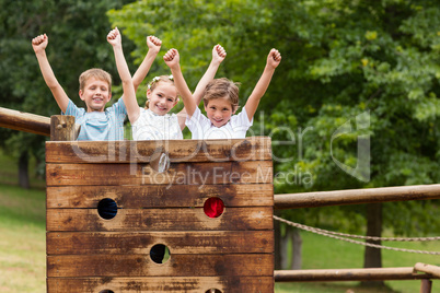 Kids standing with arms up on a playground ride in park