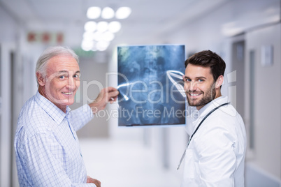 Portrait of doctor and patient holding x-ray in corridor