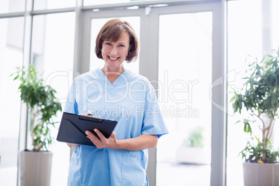 Portrait of smiling nurse writing on clipboard