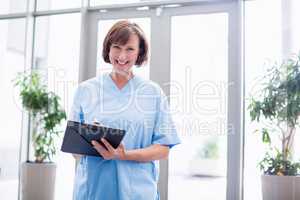 Portrait of smiling nurse writing on clipboard