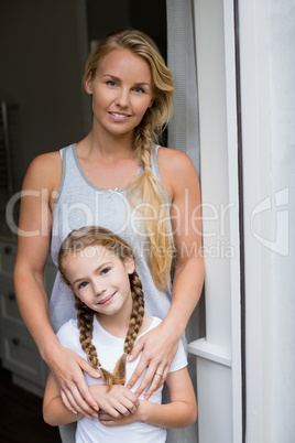 Smiling mother and daughter standing at home