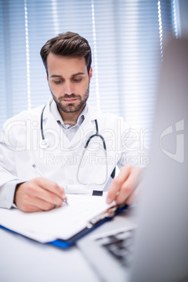 Male doctor writing on clipboard