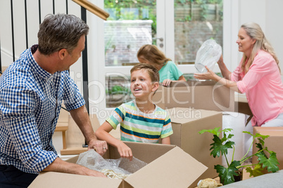 Parents and kids unpacking carton boxes in living room