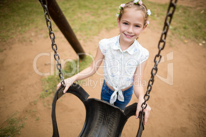 Happy girl smiling while holding a swing in park